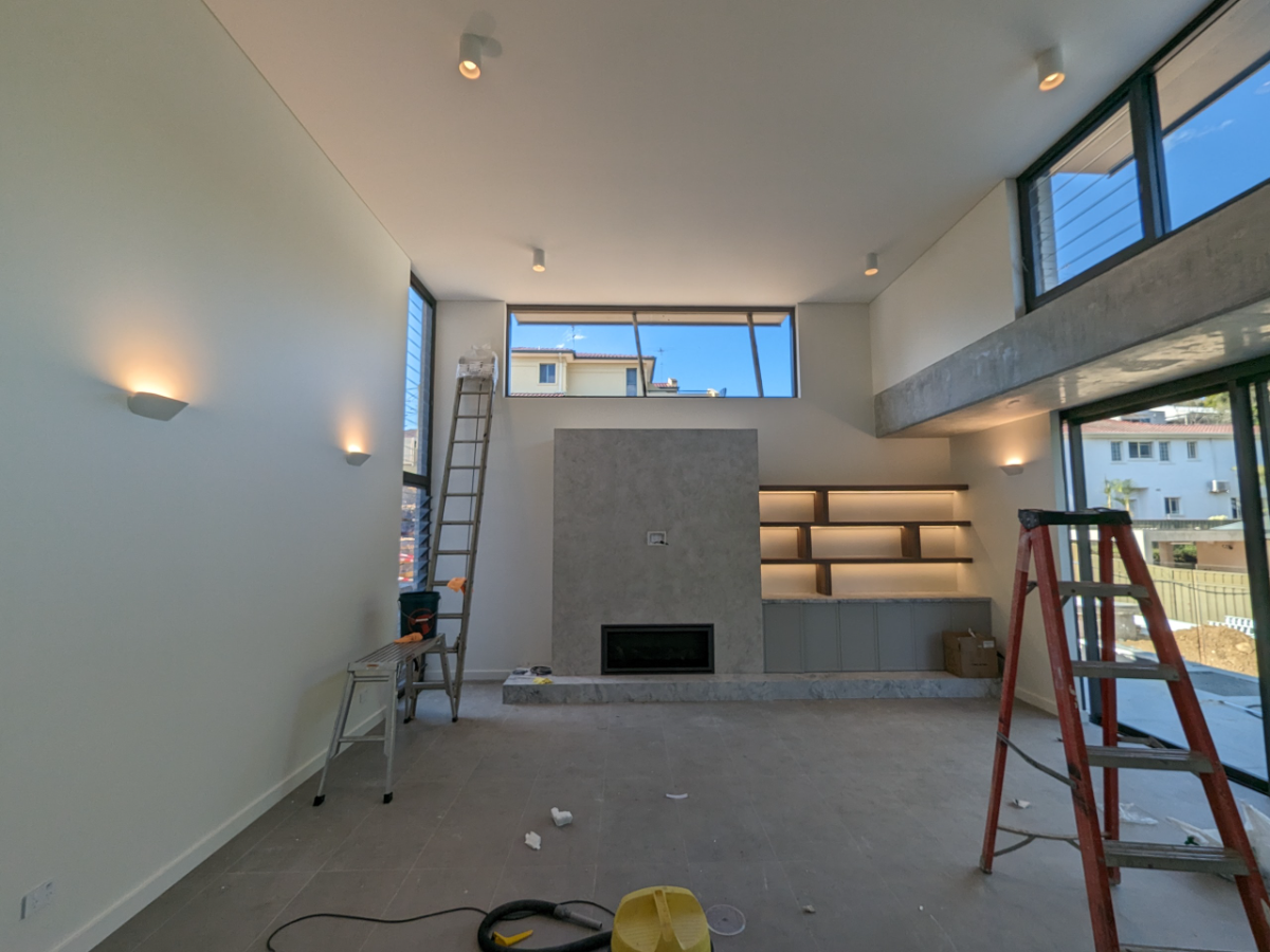 High-ceiling modern living room with feature wall sconces and LED shelf lighting, Sydney