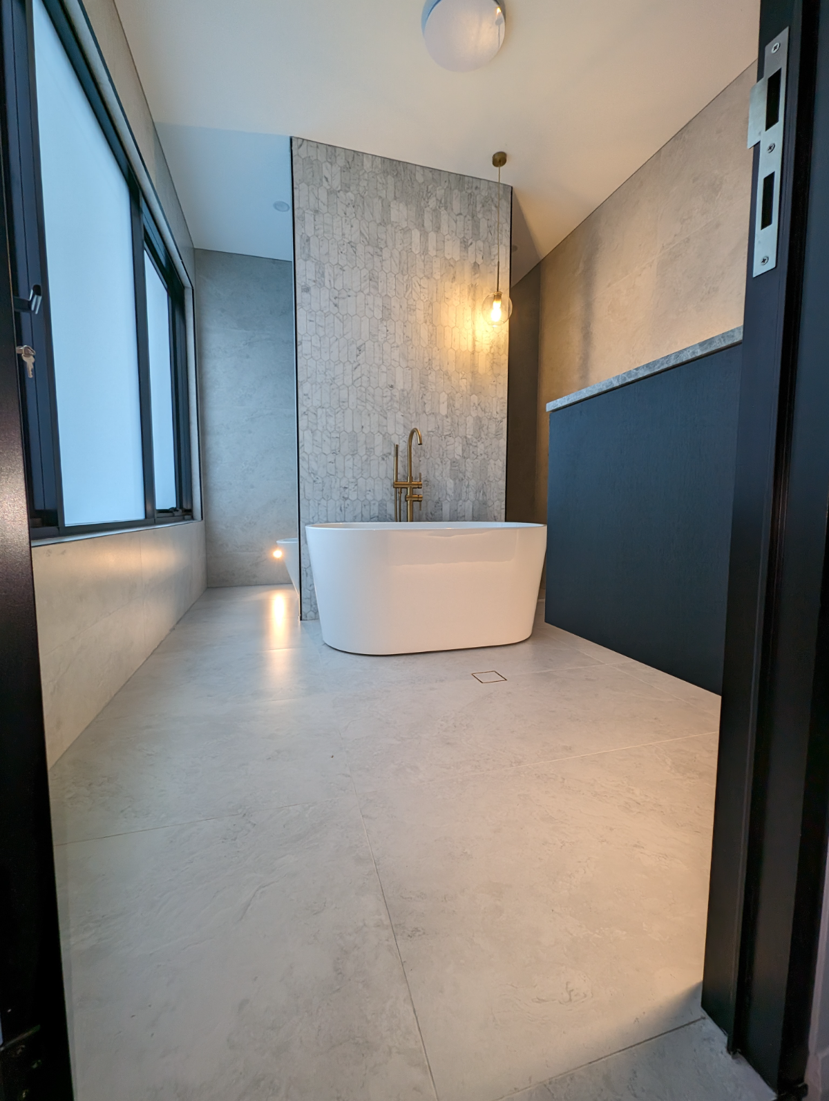 Spa bathroom with brass globe pendant and stone feature wall, Sydney