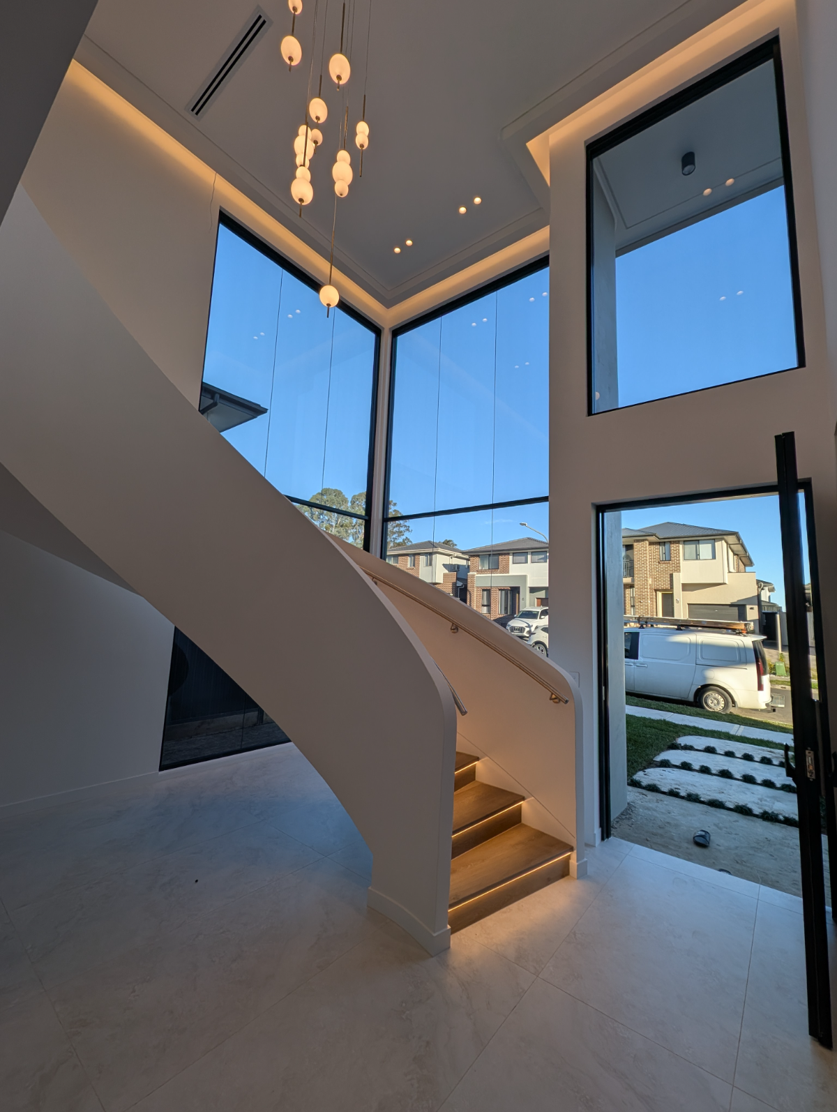 Two-storey foyer with cluster pendant and concealed LED stair lighting, Sydney